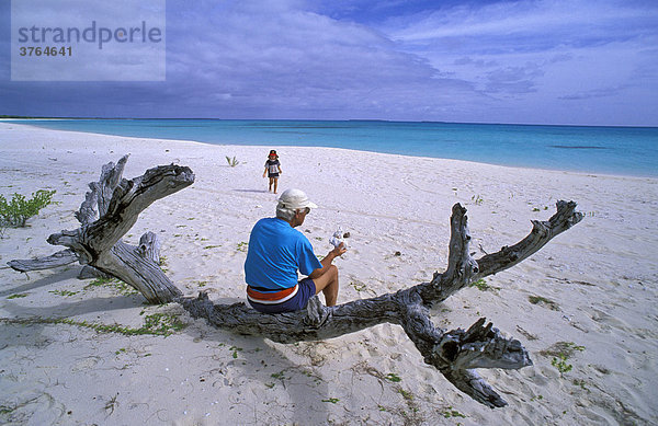 Großvater sitzt auf einem Baumstamm am Strand von Muli und wartet auf die Enkelin  Ouvea  Neu-Kaledonien