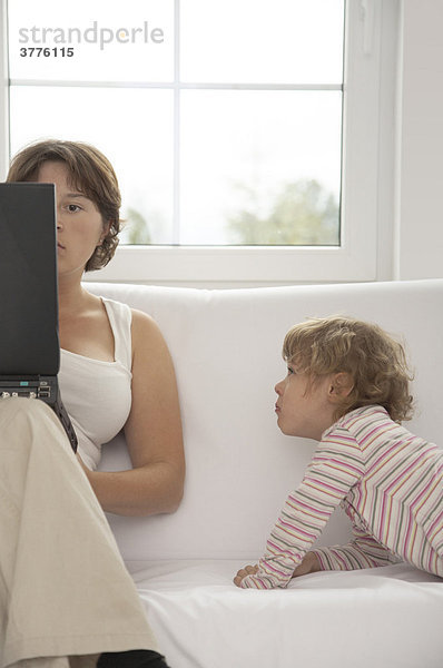 Mutter am Computer neben dem Kind
