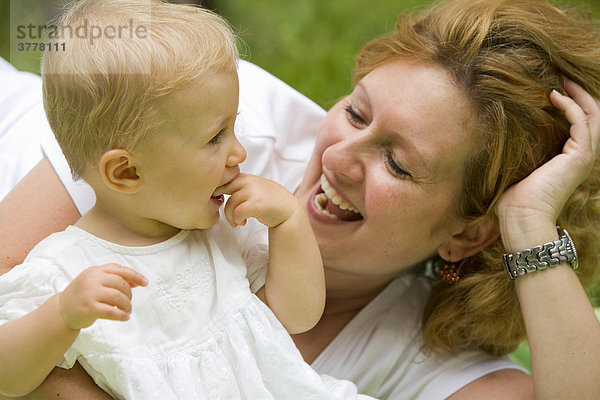 Eine junge Frau mit ihrer 10 Monate alten Tochter im Arm