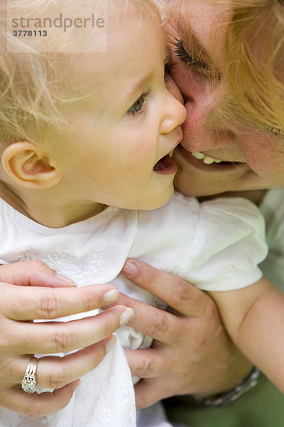 Eine junge Frau mit ihrer 10 Monate alten Tochter auf dem Arm