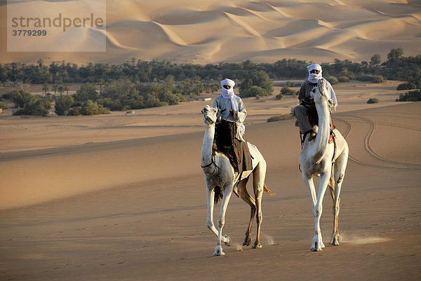 Zwei Tuareg reiten elegant auf ihren Kamelen in der Wüste Mandara Libyen