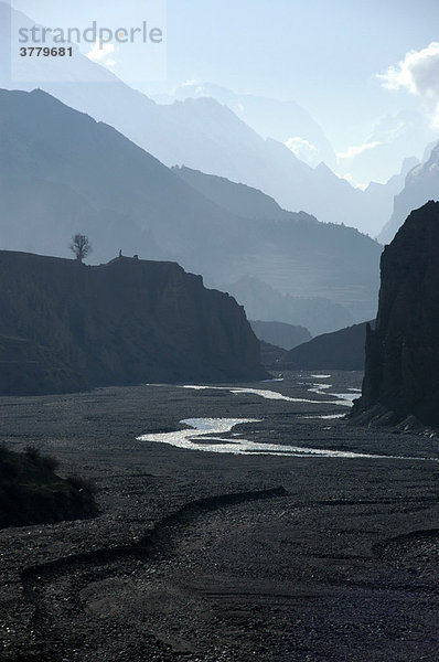 Fluß unter mehreren Gebirgszügen hintereinander im Dunst bei Manang Annapurna Region Nepal