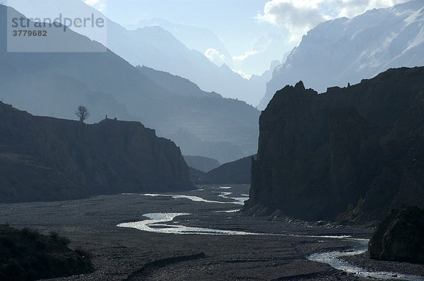 Fluß unter mehreren Gebirgszügen hintereinander im Dunst bei Manang Annapurna Region Nepal