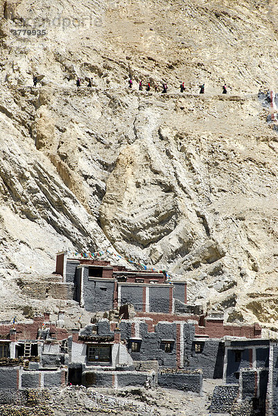 Tibetischer Buddhismus Pilger auf der Kora über privaten Häusern der Altstadt mit grau und dunkelrot gestrichener Mauer Kloster Sakya Tibet China