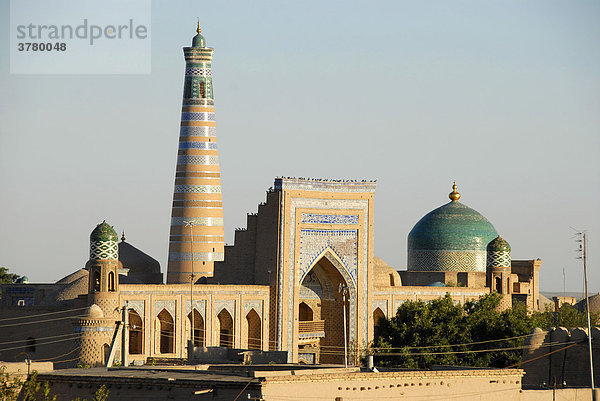 Hohes Minarett der Islom Xo'ja-Medrese und große blaue Kuppel des Pahlavon-Maxmud-Mausoleum hinter dem Iwan der Raxim Chan Medrese in der Altstadt Xiva Usbekistan