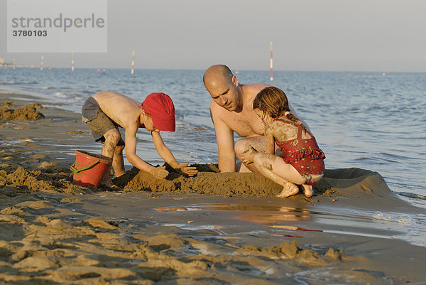 Familie baut eine sandburg am Strand