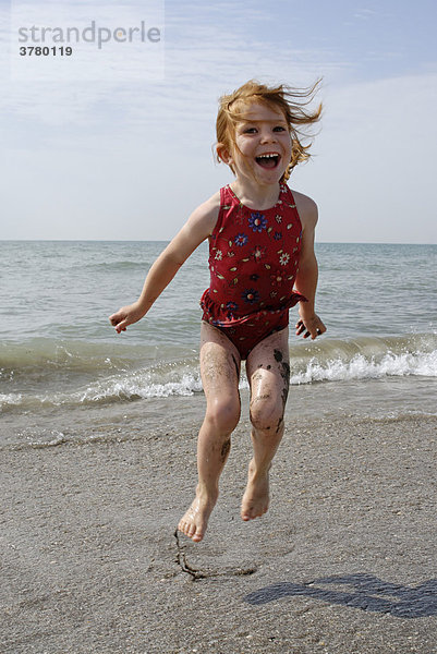 Kind hüpft am Strand in der Meeresbrandung