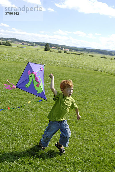 Junge läßt einen Drachen in den Wind steigen