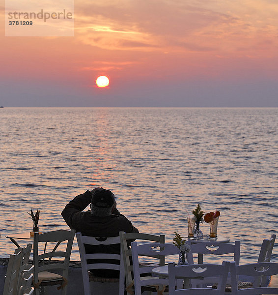 Mann fotografiert Sonnenuntergang von einem Lokal aus  Mykonos  Griechenland