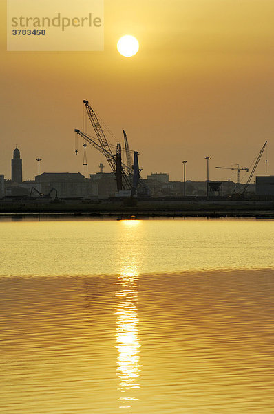 Kräne im Hafen von Chioggia bei Sonnenaufgang  die Sonne spiegelt sich im ruhigen Wasser  Chioggia  Venezien  Italien