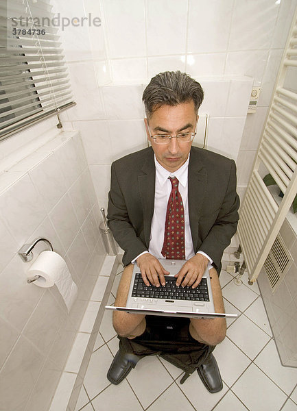 Verrückter Geschäftsmann mit Notebook auf der Toilette