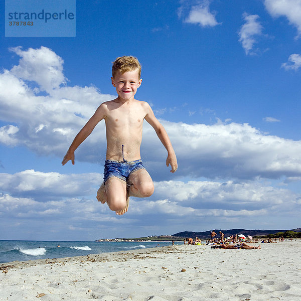 Ein Junge  5 Jahre  macht am Strand einen Freudensprung  La Caletta  Sardinien  Italien