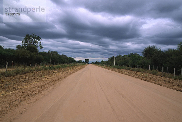 Das Ende der Trockenzeit: Wolkenverhangener Himmel über einer Landstraße  Gran Chaco  Paraguay