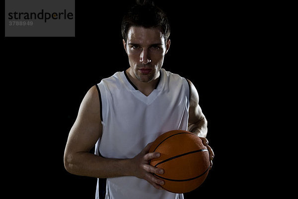 Ein Basketballspieler  der sich darauf vorbereitet  einen Ball  ein Porträt oder einen Studioschuss abzugeben.