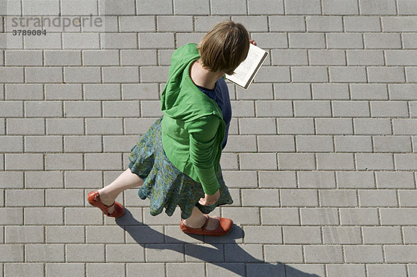 Eine Frau beim Gehen und Lesen eines Buches