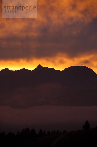 Abendhimmel mit leuchtend orangefarbenen Wolken über Gebirge Hochsavoyen Haute-Savoie Frankreich