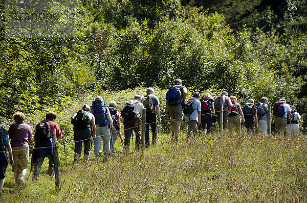 Wandergruppe geht hintereinander über eine Wiese Hochsavoyen Haute-Savoie Frankreich