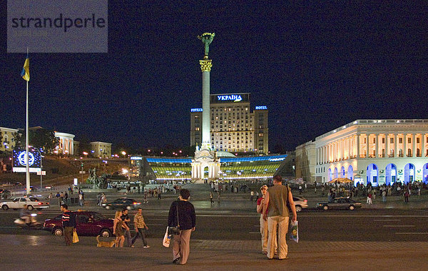 Ukraine Kiev Unabhängigkeits Platz mit Unabhängigkeitssäule Gebäude der Nationalen Musikakademie Cajkovskij Konservatorium rechts beleuchtetes Hotel Kiev mitte Musikveranstaltung Nationalfeiertag Menschen auf Platz feiern Nachthimmel Leute trinken lagern in Parkwiese 2004