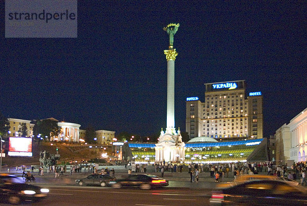 Ukraine Kiev Unabhängigkeits Platz mit Unabhängigkeitssäule Gebäude der Nationalen Musikakademie Cajkovskij Konservatorium rechts beleuchtetes Hotel Kiev mitte Autoverkehr Musikveranstaltung Nationalfeiertag Menschen auf Platz feiern Nachthimmel Leute trinken lagern in Parkwiese 2004