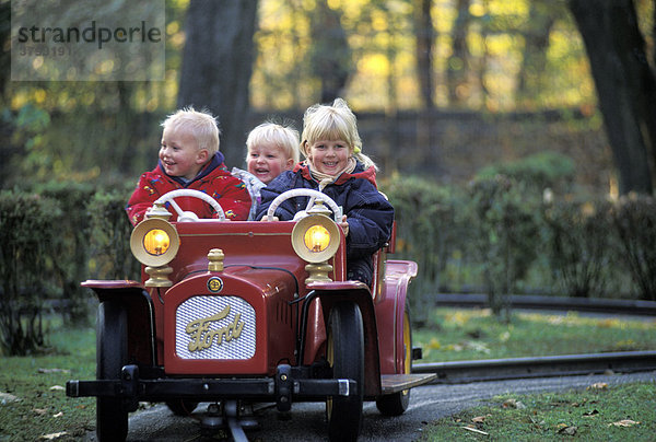 Drei Kinder in Spielzeugauto auf Geleisen