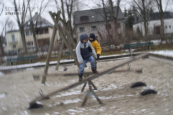 Zwei Jungen balancieren auf Wippen auf dem Kinderspielplatz