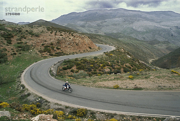 Motorradfahrer auf kurvenreicher Straße Andalusien Spanien