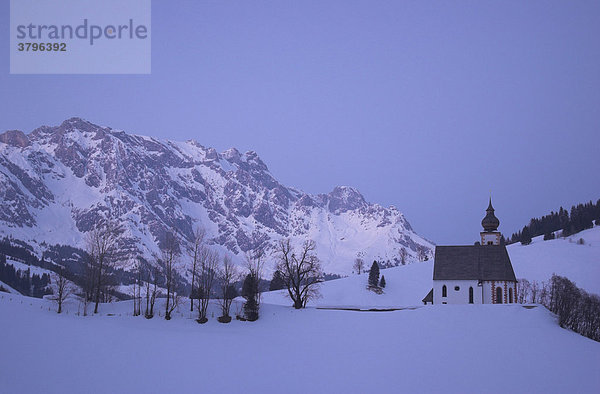 Die Kirche auf dem Bühel in Dienten vor dem verschneiten Massiv des Hochkönig in Dienten  Salzburger Land  Österreich