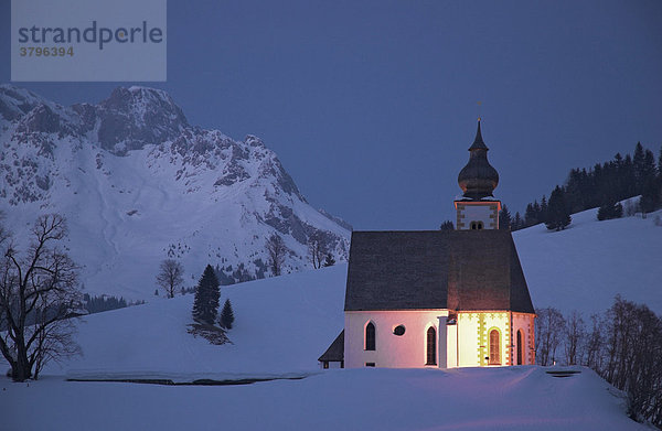 Die angestrahlte Kirche auf dem Bühel in Dienten in der Abenddämmerung  Salzburger Land  Österreich