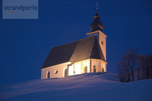 Die angestrahlte Kirche auf dem Bühel in Dienten in der Abenddämmerung  Salzburger Land  Österreich