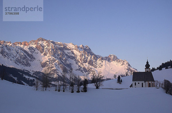 Die Kirche auf dem Bühel in Dienten vor dem verschneiten Massiv des Hochkönig in Dienten  Salzburger Land  Österreich