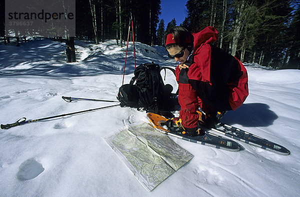 Frau studiert die Landkarte bei einer Schneeschuh-Wanderung im Karwendel Deutschland