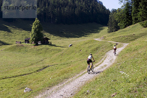 Zwei Mountainbikerinnen auf flachem Schotterweg auf sommerlicher Almwiese im Wilden Kaiser (Österreich)