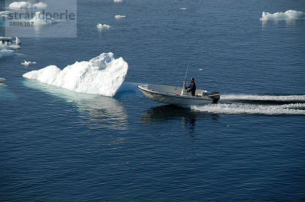 Offenes Motorboot vor Eisberg fährt durchs Packeis Ammassalik Fjord Ostgrönland