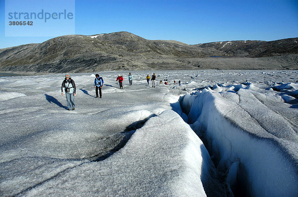 Menschen wandern auf dem Inlandeis mit Gletscherspalte Apuserserpia Gletscher Ostgrönland