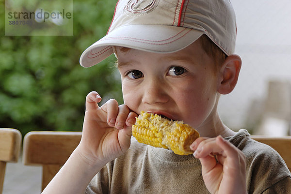 Kleiner Junge nagt isst an einem Maiskolben
