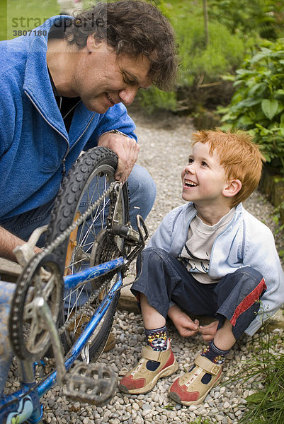 Vater hilft seinem Sohn beim Fahrrad reparieren