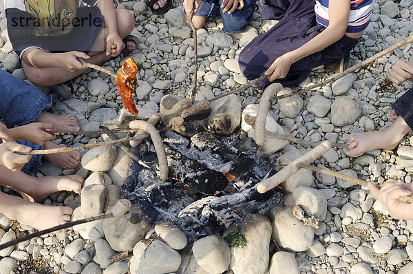 Kinder beim Würstel grillen am Feuer