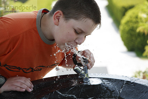 Zwölfjähriger Bub trinkt Wasser