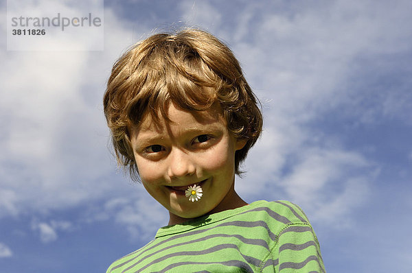 Neunjähriger Junge mit Gänseblümchen im Mund
