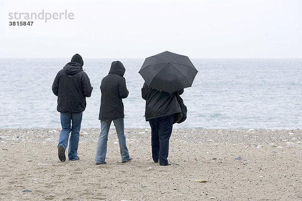 Drei Spaziergänger bei schlechten Wetter an einem Strand in der Nähe von Antalya Türkei