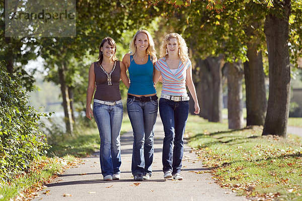 Drei Freundinnen beim Spaziergang durch einen Park