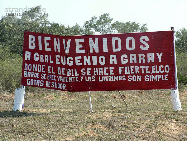 Sarkastisches Willkommensschild an der einsamen Militärstation General Eugenio Agarray an der menschenleeren Grenze zwischen Paraguay und Bolivien (Willkommen bei General Eugenio Agarray  wo der Schwache stark wird  der Feige mutig wird und Tränen nur Schweißtropfen sind)