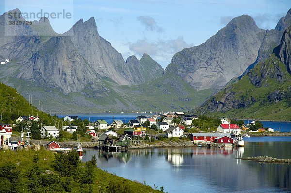 Spitze Berge und Häuser spiegeln sich im Fjord Reine Moskenesöya Lofoten Norwegen