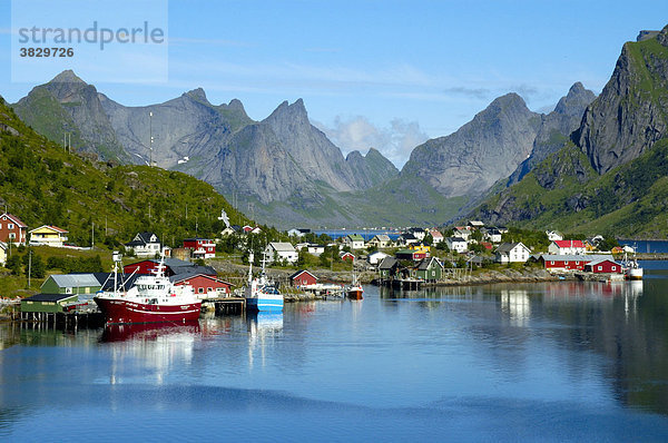 Berge Schiffe und Häuser spiegeln sich im Fjord Reine Moskenesöya Lofoten Norwegen