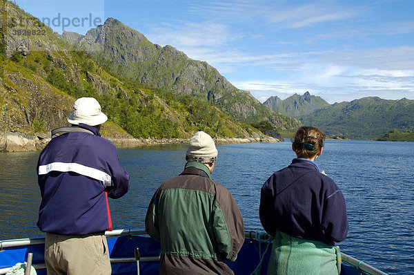 MR Drei Menschen stehen im Bug eines Boots und betrachten die Landschaft Lofoten Norwegen