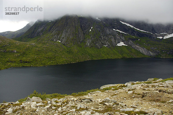 Berge und See Storvatnet unter dichter Wolkendecke Flakstadöya Lofoten Norwegen