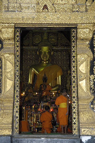 Goldene Buddha Statue und betende Mönche im Kloster Wat Xieng Thong Luang Prabang Laos