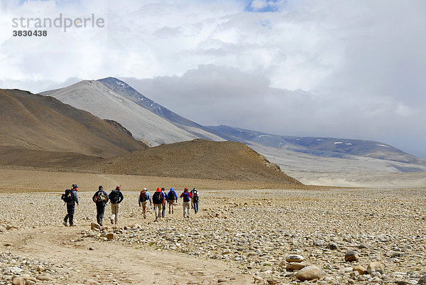 Trekkinggruppe geht über ein weites ebenes Flußtal in starkem Sturm bei Lungchang Tibet China