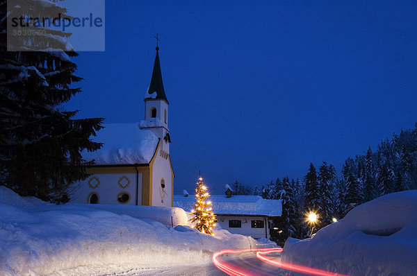 Am Achenpass bei Glashütte Oberbayern Deutschland Dorfkirche mit beleuchtetem Christbaum Weihnachtsbaum