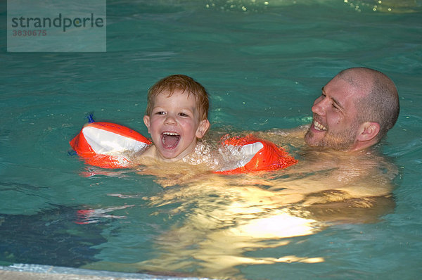 Kind schwimmt mit seinem Vater im Swimmnigpool